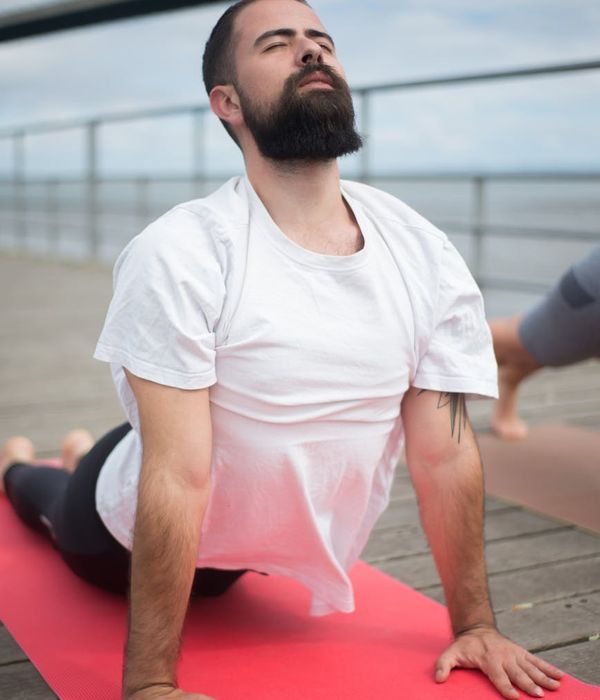 Man doing a stretching exercise on a yoga mat in a calm setting.